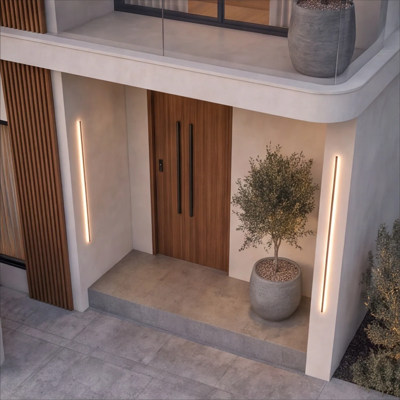 The entrance porch with a timber door, long black pulls, linear wall lights and a potted olive tree